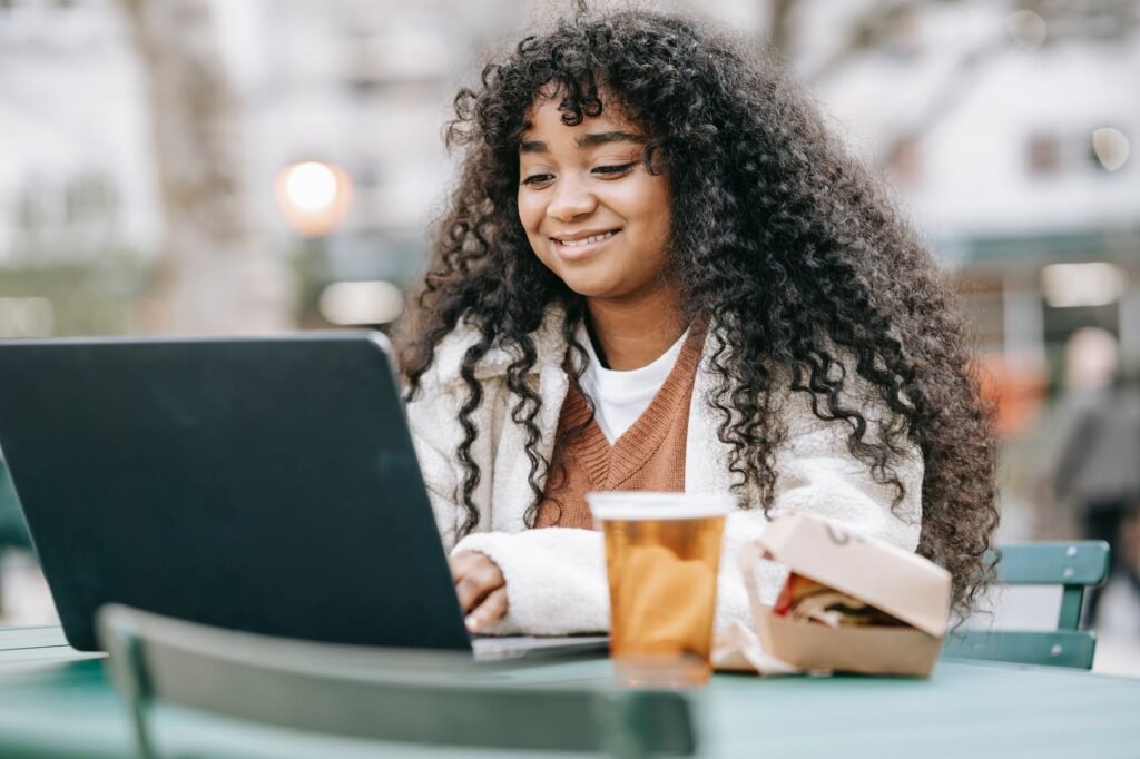 smiling black woman using laptop in city park